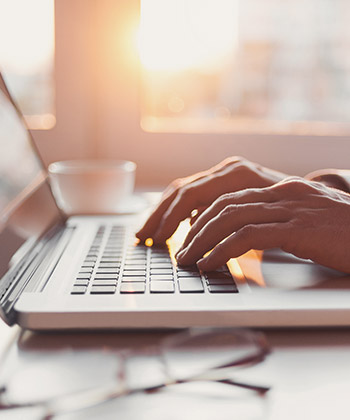 close up of hands typing on a laptop keyboard