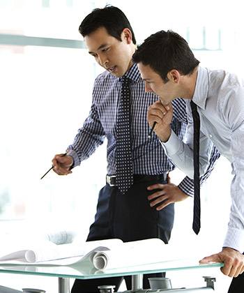 Recherche efficace de l'information adéquate two businessman standing over and studying some forms